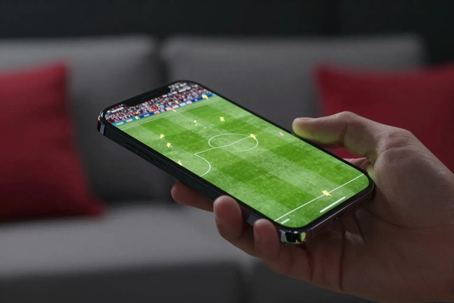 Hand holding a phone playing a live football match